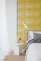 Breakwater Mimosa wallpaper in an Arent & Pyke bedroom, adding soft geometric pattern behind a white bed.